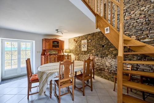 une salle à manger avec une table et un mur en pierre dans l'établissement Au Pré des Dunes - A 4 km de la plage, à Saint-Rémy-des-Landes