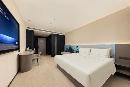 Un dormitorio con una cama blanca y un televisor de pantalla plana. en Atour Light Hotel Suzhou Guanqian Street Chayuanchang Subway Station, en Suzhou