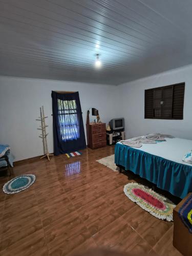 a bedroom with a bed and a wooden floor at Rancho Pé da Pedra in São Bento do Sapucaí