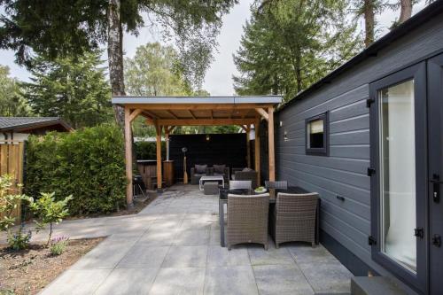 a patio with chairs and a pavilion with trees at Luxe Chalet Veluwe Sauna en Hottub in Hoenderloo