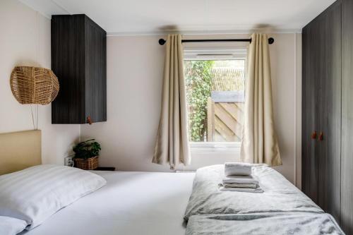 a bedroom with a bed and a window at Luxe Chalet Veluwe Sauna en Hottub in Hoenderloo