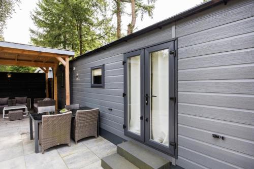 a building with a patio with a table and chairs at Luxe Chalet Veluwe Sauna en Hottub in Hoenderloo