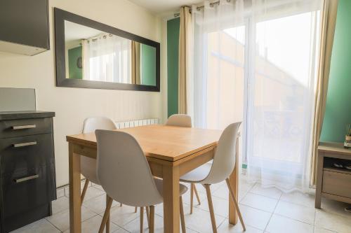 - une table à manger avec des chaises blanches et un miroir dans l'établissement Cosy en centre ville, à Amiens
