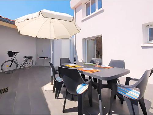 - une salle à manger avec une table et un parasol dans l'établissement Maison de vacances à 500m de la plage avec stationnement, à Les Sables-dʼOlonne