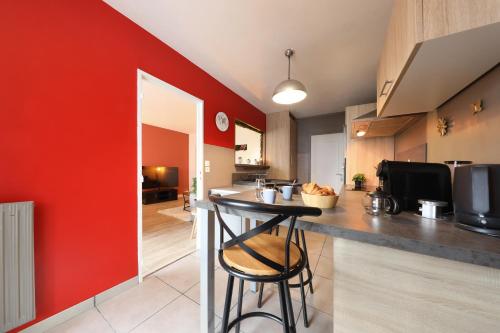 a kitchen with a counter and a red wall at Le Cocon des Pros', calme, spacieux et tout équipé in Compiègne