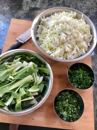 a wooden cutting board with bowls of cabbage and onions at The Cowshed Cottage on The Greenway in Dungarvan
