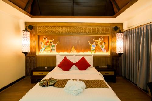 a bedroom with a large bed with red pillows at Nak Nakara Hotel in Chiang Rai