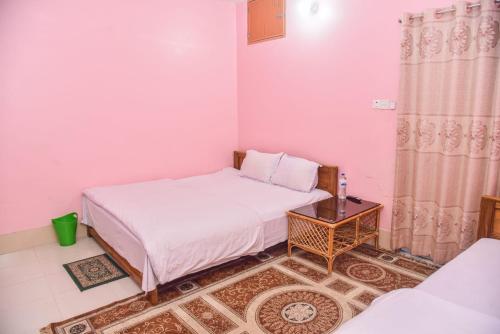 a small bedroom with two beds and a table at Al Hera Resort in Sreemangal