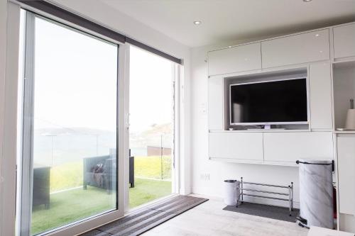 a living room with a tv and a large sliding glass door at 2 Bedroom Chalet With Sea Views in Plymouth