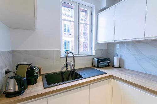une cuisine avec un évier et un micro-ondes dans l'établissement Luxury Apartment Neuilly, à Neuilly-sur-Seine