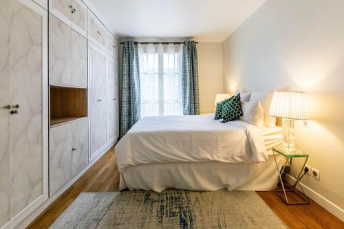 une chambre blanche avec un lit et une fenêtre dans l'établissement Luxury Apartment Neuilly, à Neuilly-sur-Seine