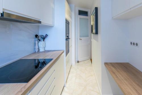 La cuisine est équipée de placards blancs et d'un évier bleu. dans l'établissement Luxury Apartment Neuilly, à Neuilly-sur-Seine
