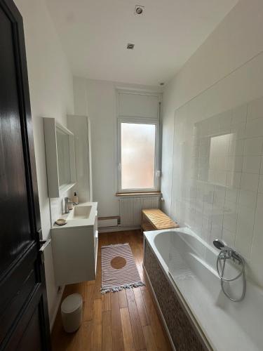une salle de bain blanche avec une baignoire et un lavabo dans l'établissement La Malouine Dunkerquoise HomyNest, à Dunkerque