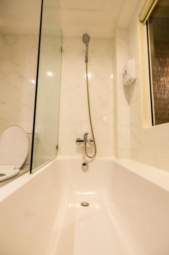 a white bath tub in a bathroom with a shower at Nak Nakara Hotel in Chiang Rai