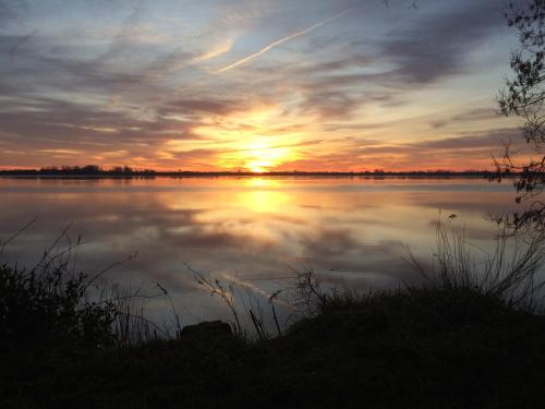 - un coucher de soleil sur un lac au coucher du soleil dans l'établissement Cottage du Capitaine, à La Reuille