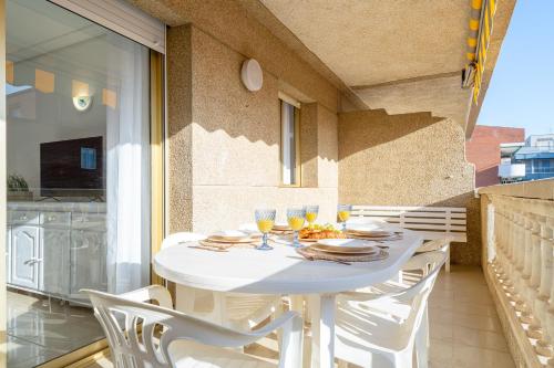 a white table with chairs and wine glasses on a balcony at ALBENIZ Superior in La Pineda