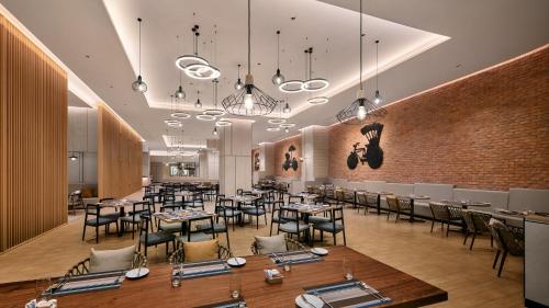 a restaurant with tables and chairs and a brick wall at Holiday Inn & Suites Penang Prai by IHG in Bukit Mertajam