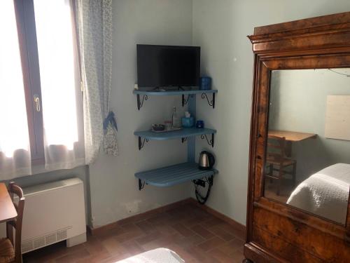 a bedroom with a bed and a television and shelves at Agriturismo Villa Greggio in Casalserugo