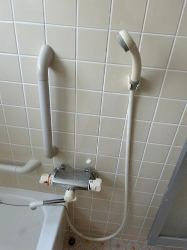 a shower in a bathroom with pipes on the wall at Shingu Guest House SOU 別館 in Shingu