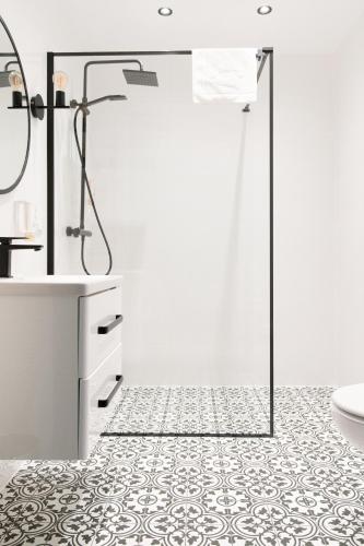 a bathroom with a shower and a tile floor at Urocza Art Pensjonat in Krynica Zdrój