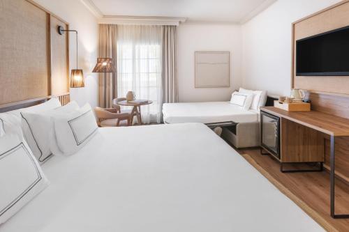 a hotel room with two beds and a television at Meliá Isla Canela in Isla Canela