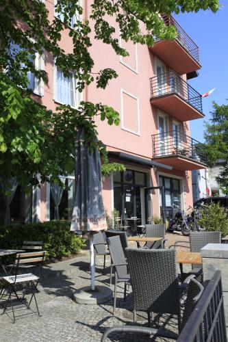 a group of chairs and an umbrella in front of a building at Willa Park Międzyzdroje in Międzyzdroje
