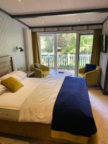 a bedroom with a large bed and a balcony at Sandy Balls Holiday Park Pet Friendly Lodge in Fordingbridge