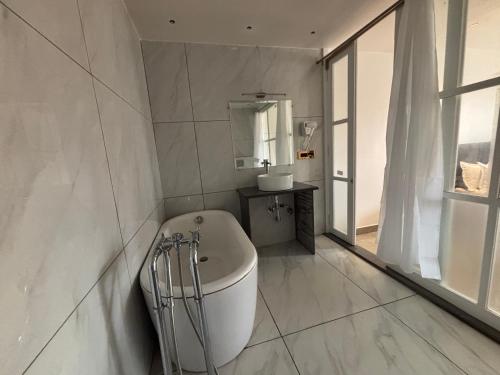 a white bathroom with a tub and a sink at Baga Beach Sea Salacia in Goa