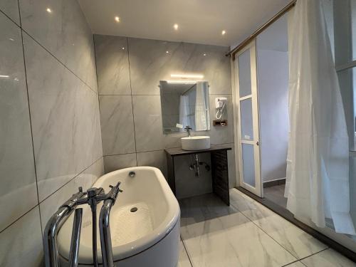 a white bathroom with a tub and a sink at Baga Beach Sea Salacia in Goa