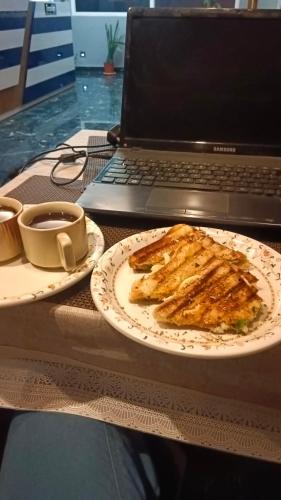 a table with a plate of food and a laptop at THE VISTA RESIDENCY in Guwahati