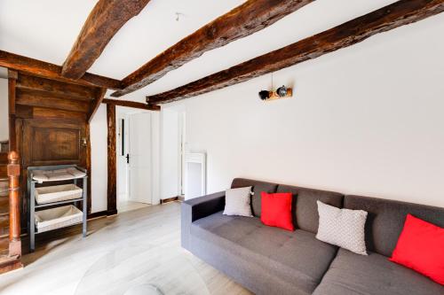 ein Wohnzimmer mit einem grauen Sofa und roten Kissen in der Unterkunft Maison moderne, en pierre avec terrasse pour 6 in Montignac