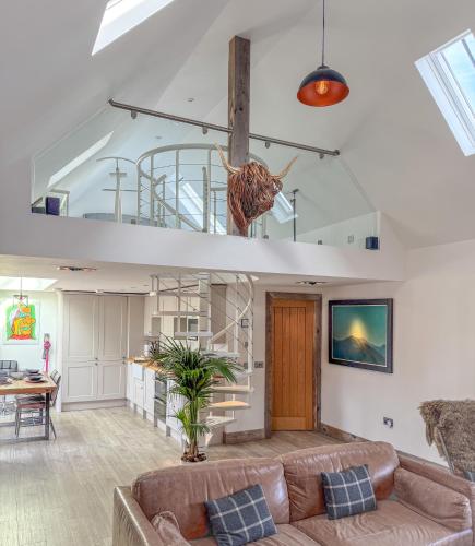 a living room with a couch and a staircase at Balloan Cottage Cowshed in Inverness