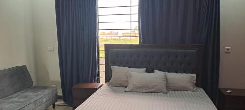 a bedroom with a bed and a window with blue curtains at 430 Islamabad in Islamabad