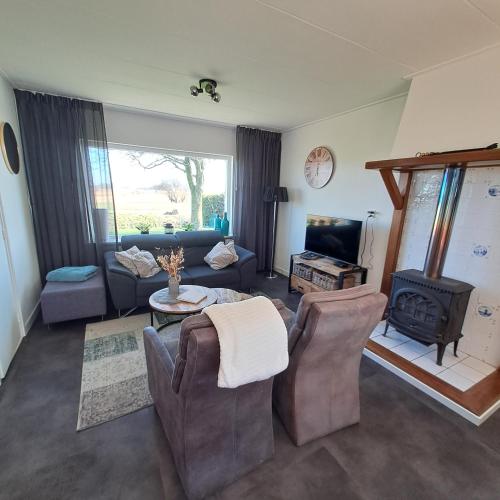 a living room with a couch and chairs and a stove at Vakantiehuisje 't Wiede in Blokzijl