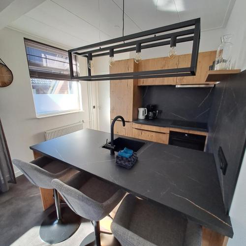 a kitchen with a black table and some chairs at Vakantiehuisje 't Wiede in Blokzijl