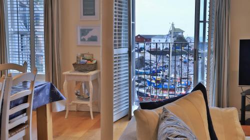 a living room with a view of a harbor through a window at Harbourside Apartment in Mevagissey