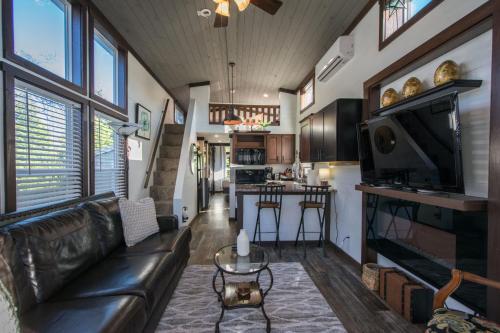 a living room with a leather couch and a kitchen at Gorgeous 1BR Tiny Home with Pool and Bocce in Flat Rock