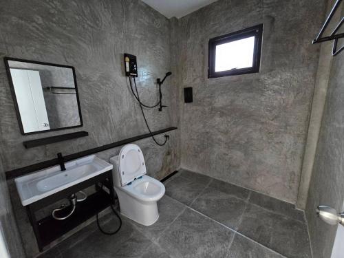 a bathroom with a toilet and a sink and a mirror at เลอร์กบินทร์ in Kabin Buri