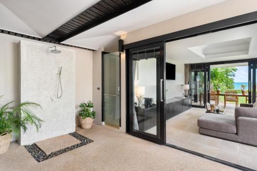a living room with glass doors and a couch at Nikki Beach Resort & Spa Koh Samui in Lipa Noi