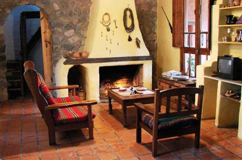 sala de estar con chimenea, 2 sillas y mesa en Rincon del Valle en San Salvador de Jujuy