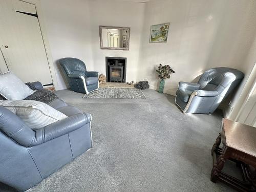 a living room with two blue leather chairs and a fireplace at Traditional Inveraray Cottage - Amazing Loch Views in Inveraray