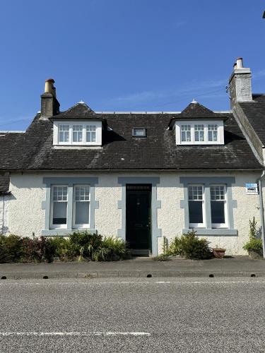 a white house with a black door on a street at Traditional Inveraray Cottage - Amazing Loch Views in Inveraray