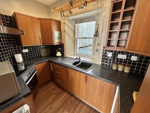 a kitchen with wooden cabinets and a sink and a window at Traditional Inveraray Cottage - Amazing Loch Views in Inveraray