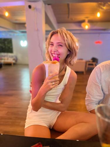 a woman sitting on the floor eating a doughnut at Tiki Tribe Bar & Hostel in Koh Tao