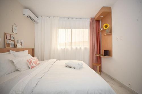 a bedroom with a large white bed with a window at Un cocon en plein centre ville! En Caze Likouala in Libreville