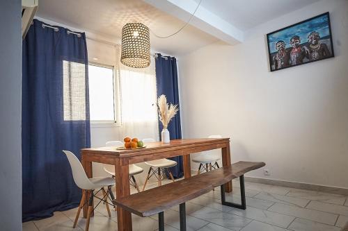 a dining room with a wooden table and chairs at Un cocon en plein centre ville! En Caze Likouala in Libreville