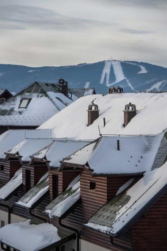 a group of roofs covered in snow with mountains in the background at Zlatiborski Konaci in Zlatibor
