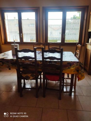 - une table à manger avec 2 chaises et 2 fenêtres dans l'établissement 3 Chambres chez l'habitant, à Valleiry