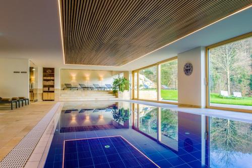 einen Innenpool mit blauen Fliesen und Fenstern in der Unterkunft Design-Chalet with Garden, Pool, Spa & Restaurant in Lochau