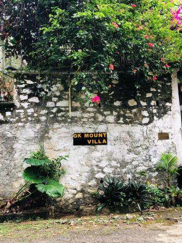 a sign on the side of a stone wall with flowers at GK Mount Villa Kandy in Kandy